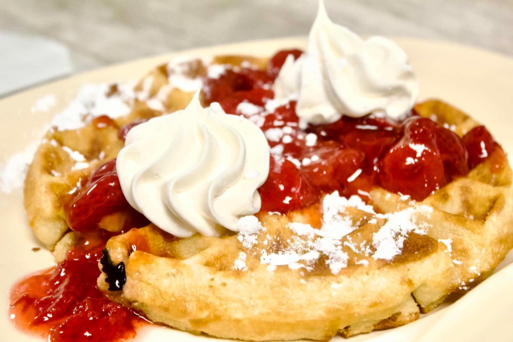 Waffle topped with strawberries and whipped cream